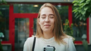 joyful girl drinks tea on the street in rainy weather, and speaks on the phone