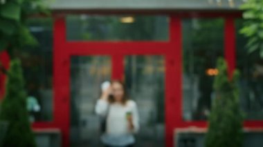 joyful girl drinks tea on the street in rainy weather, and speaks on the phone