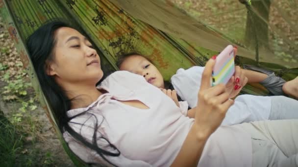 Счастливая Азиатская Женщина Вместе Дочерью Смотреть Кино Гамаке Насладиться Отдыхом — стоковое видео