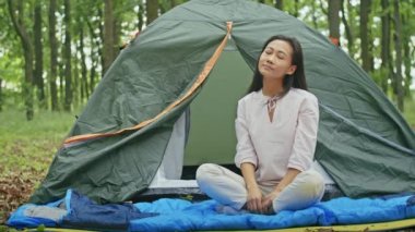 Mutlu Asyalı kadın Forest City Park 'ta çadırda dinlenirken temiz havanın tadını çıkarıyor. yaz kampı