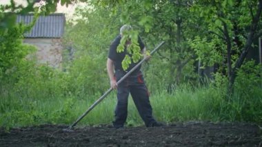 The farmer works with a rake in the garden. Agriculture. Agronomist on a collective farm. The worker works on the farm. Agriculture concept. Business Farm, Spring.