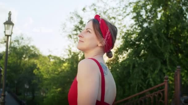 穿着红衣服的快乐女孩在公园里散步 享受夕阳西下的街道 享受夏日的生活 — 图库视频影像