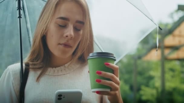 Joyful Girl Drinks Tea Street Umbrella Rainy Weather Speaks Phone — Video