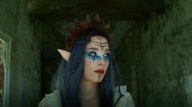 Profesyonel makyajlı güzel bir kızın portresi. Başında çiçek tacı olan elf prensesi. Cadılar Bayramı renkli makyaj. Parlak yüz sanatı. bahar çiçekleri