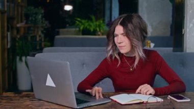 Masasında bilgisayar ve telefonla oturan bir kadın..