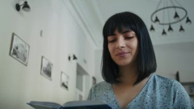 Mutlu ve hayalperest kadın kütüphanede kitap okuyor, raftan kitap seçiyor. Öğrenciler için kütüphanede öğrenim.