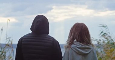 Sonbahar ormanlarında mutlu genç bir çift duygularını gösterir, adam ağacın yanındaki kıza sarılır.