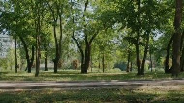 Neşeli kız yazın tadını çıkarıyor ve park ve şehir sokaklarında scooter sürüyor.