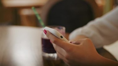 Kafede çay içip telefonda ya da görüntülü konuşma yapan neşeli bir kız. İyi eğlenceler.