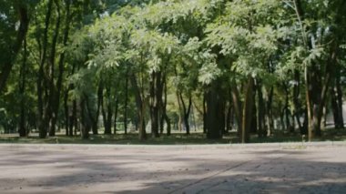 Neşeli kız yazın tadını çıkarıyor ve park ve şehir sokaklarında scooter sürüyor.