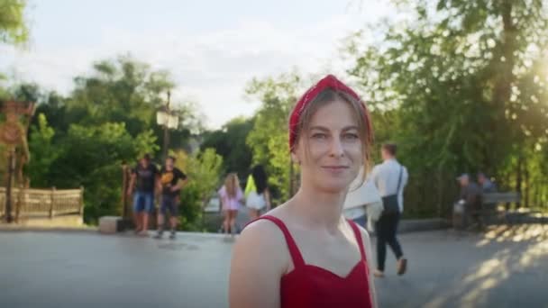 公園を歩く赤いドレスの幸せな女の子路上で夕日を楽しんで夏のライフスタイル — ストック動画