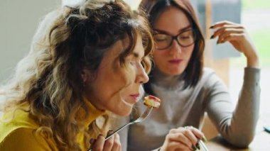 İki genç ve mutlu kadın reçelli lezzetli şurubun tadını çıkarıyorlar. Sıcak yaz mevsiminde güzel bir yerde çatalla yiyorlar.