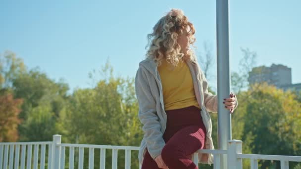 ガラスの幸せな若い女性が街の公園の橋を歩いています 秋の夏 — ストック動画