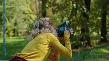 Şehir parkının arka planında poz veren mutlu genç kız arkadaşı fotoğrafçıya. gençlik ve güzellik