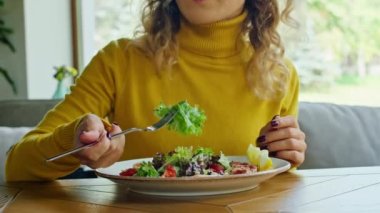 two young happy women enjoy delicious salad of chicken, tomato and croutons, eat it with a fork in a beautiful cool place in hot summer