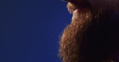 Close-up of a European podcast blogger smiling while broadcasting his live audio podcast in a studio using a microphone and headphones. Male radio host with glasses, podcast host or interviewer.