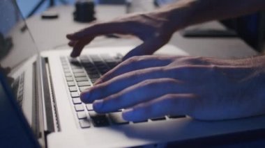 Yakın plan, erkek bir video editörünün elleri stüdyodaki bir dizüstü bilgisayarda işlem görüyor.