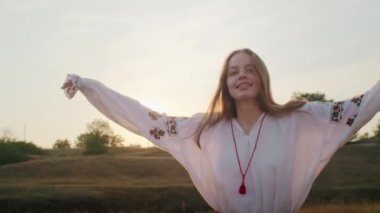happy young woman enjoying the sunset, wearing traditional ukrainian clothes. lifestyle in Ukraine