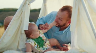 Childs 'ın yaşam tarzı. Sonbahar tarlasında mutlu yıllar. Gün batımında küçük çocuk, çadırda pastayla. Fotoğrafçı doğum günü fotoğrafı çekiyor. Aile ve bebek sevinci
