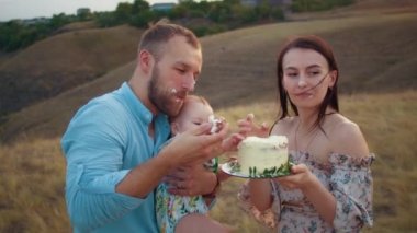 Bebekle mutlu bir aile ilk yılı kutlar, gün batımında, sonbaharda ve yaşam tarzında pasta yerler.