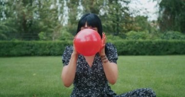 a happy joyful woman inflates balloons and they burst, showing that everything is wrong with condoms and they are torn. playful emotion, pereponyayuschie anger and happiness.
