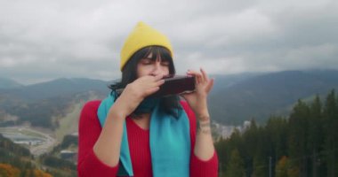 Dağlarda genç bir kadın gezgin sıcak bir içecekle ısınıyor. Sonbahar maceraları. Z kuşağı yolculuğu.