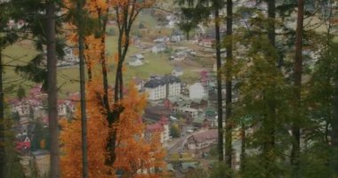 Bukovel kayak merkezinin manzarası, güzel sonbahar ağaçları ve dağlar, uzaktaki evler.
