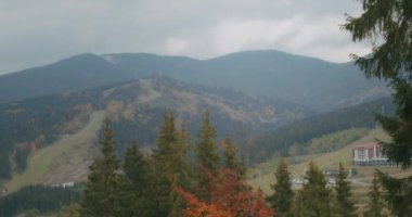 Bukovel kayak merkezinin manzarası, güzel sonbahar ağaçları ve dağlar, uzaktaki evler.
