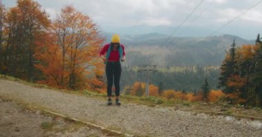 Genç bayan gezgin dağlarda serin sonbahar havasının tadını çıkarıyor ve eğleniyor. Sonbahar soğuk havası. Z kuşağı yolculuğu.
