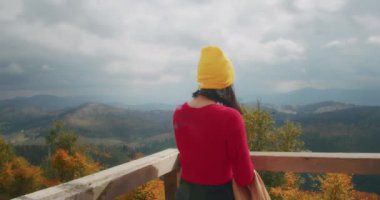 Dağlarda genç bir kadın gezgin kalın giysiler giyer. Sonbahar soğuk havası. Z kuşağı yolculuğu.