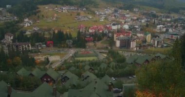 Bukovel kayak merkezinin manzarası, güzel sonbahar ağaçları ve dağlar, uzaktaki evler.