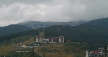 Bukovel kayak merkezinin manzarası, güzel sonbahar ağaçları ve dağlar, uzaktaki evler.