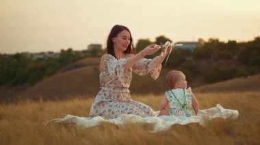 Childs 'ın yaşam tarzı. Sonbahar tarlasında mutlu yıllar. Gün batımında küçük çocuk, çadırda pastayla. Fotoğrafçı doğum günü fotoğrafı çekiyor. Aile ve bebek sevinci