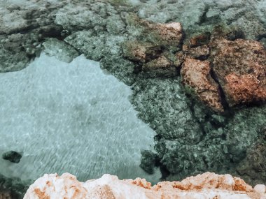 Lagre taşları suda. Kıbrıs yakınlarındaki Akdeniz 'de. Kayalık deniz yatağı beyaz kum ve berrak mavi suyla kaplı..