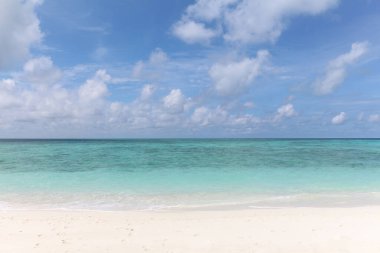 Maldivler, turkuaz okyanusun yanında beyaz kumlu bir sahil. Açık ufuk çizgisi.