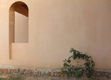 Arap binasının duvarında kemerli bir pencere. Duvardaki hafif gölgeler.