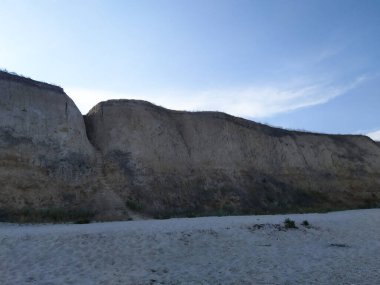 Sandy cliffs over the sea. High seashore landscape. Steps carved into the rock that lead to the sea.