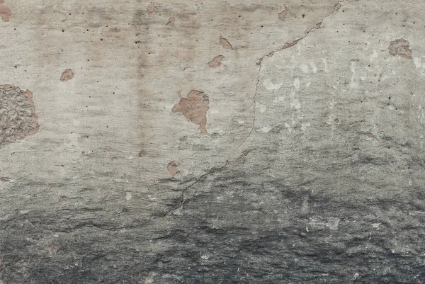 A weathered wall background with cracks and damages. A plaster old wall with grunge texture in shades of grey, beige and white. Easily add depth to your designs. Minimal urban photo.