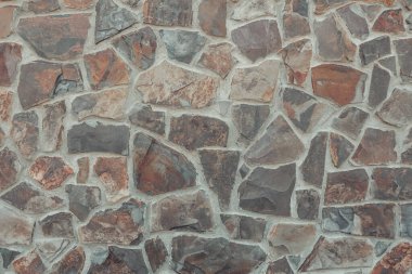 Detaylı doğal dokusu olan taştan bir döşeme. Eski taş duvar, yumuşak gri kırmızı palete bürünmüş. Tarihi bina cephesi. Tasarımlarınıza kolayca derinlik ve organik doku ekleyin.