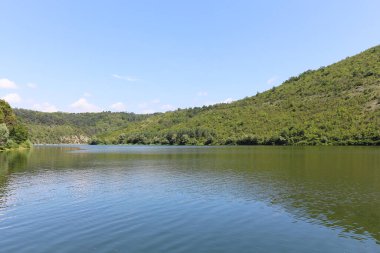 Sakin suyu olan büyük bir nehrin yeşil kıyıları. Dniester Nehri 'nin Ukrayna' daki kollarının manzarası. Yeşil tepeler, panoramik nehir manzarası sakin renklerde. Yaz günü.