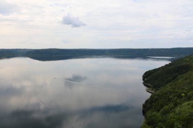 A smooth calm water view. The banks of a large river. The panoramic landscape of Bakota Bay view. Dniester river, Ukraine. High banks, green hills. Summer day.