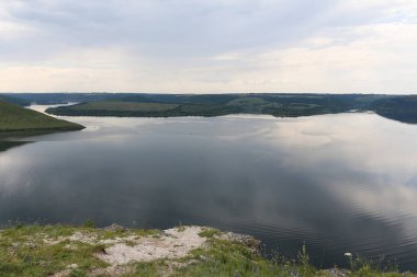 The banks of a large river. A calm smooth water view. The landscape of Bakota Bay on the Dniester river, Ukraine. High banks, green hills. Summer day.