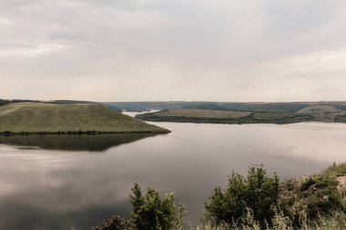 Büyük bir nehrin kıyısında. Bakota, Dinyester Nehri, Ukrayna. Pürüzsüz sakin su panoramik manzarası. Yüksek bankalar, yeşil tepeler. Doğu Avrupa 'da yaz günü.