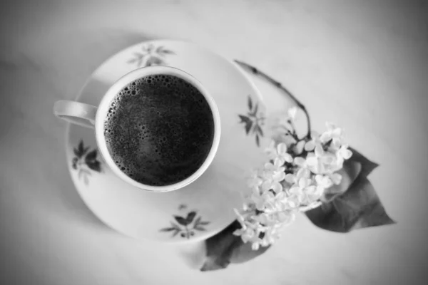 一杯咖啡放在桌子上 上面有一枝黑白相间的丁香 — 图库照片