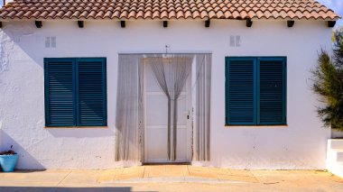 Mavi kapılı ve pencereli beyaz kulübe.