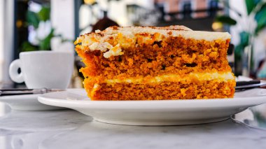 Havuç ve kremalı pastanın yanında altta bir fincan kahve var.