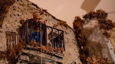 detail of Nativity scene: woman at the balcony with rope.