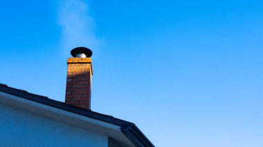 Çatıdaki baca tenceresinin ayrıntıları ve altında mavi gökyüzü var.