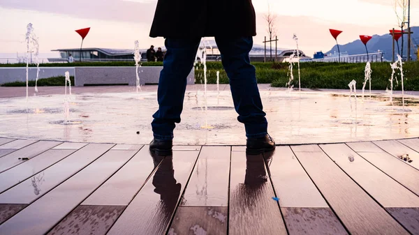 legs of man in front of fountain in Piazza della Liberta, Salerno, Italy