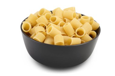Beyaz arka planda izole edilmiş seramik kasede çiğ İtalyan makarnası. Mezze Maniche Rigate Bronz Zarı.